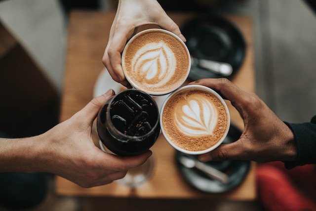 three people holding coffee cups