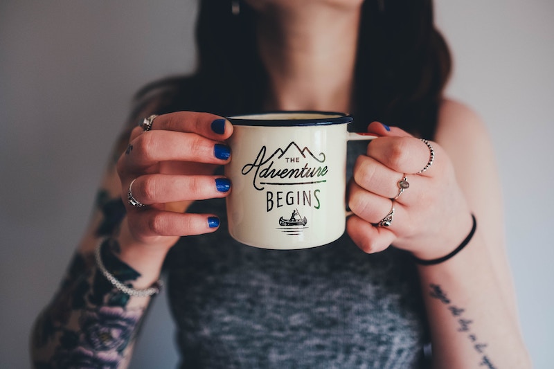 Woman with arm tattoos holding coffee mug